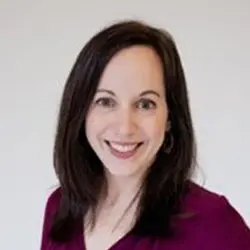 A woman in a purple shirt smiling for the camera.