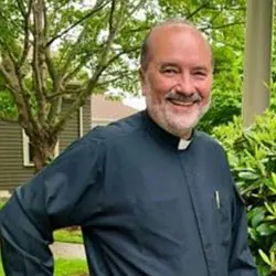 A man in a priest 's outfit standing outside.