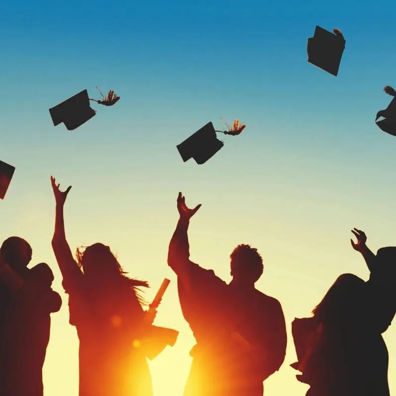 A group of people that are throwing their hats in the air.