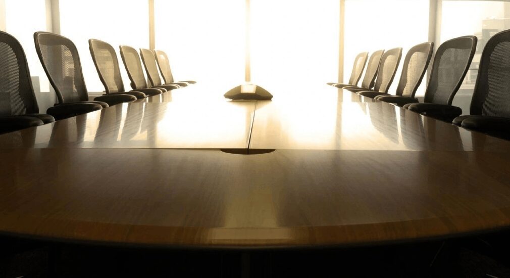 A conference table with chairs in front of the window.