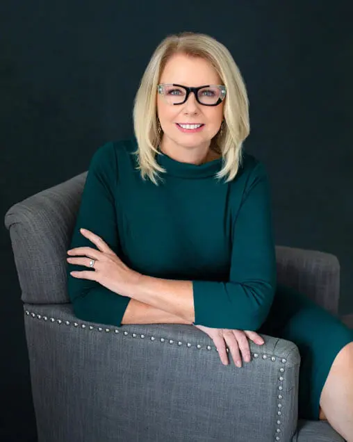 A woman sitting in a chair wearing glasses.