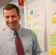 A man standing in front of a wall covered with post it notes.